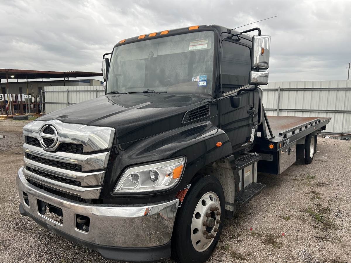 MankStar tow truck carrying a vehicle at a salvage yard.
